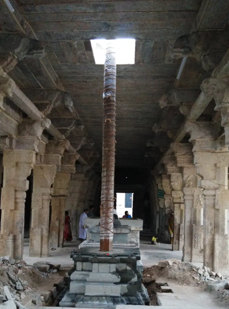 A tall flagstaff wrapped in rope stands in a long stone hall with carved pillars.