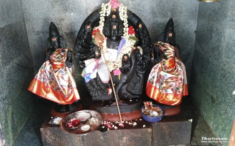 A garlanded multi-armed Murugan between two draped goddesses