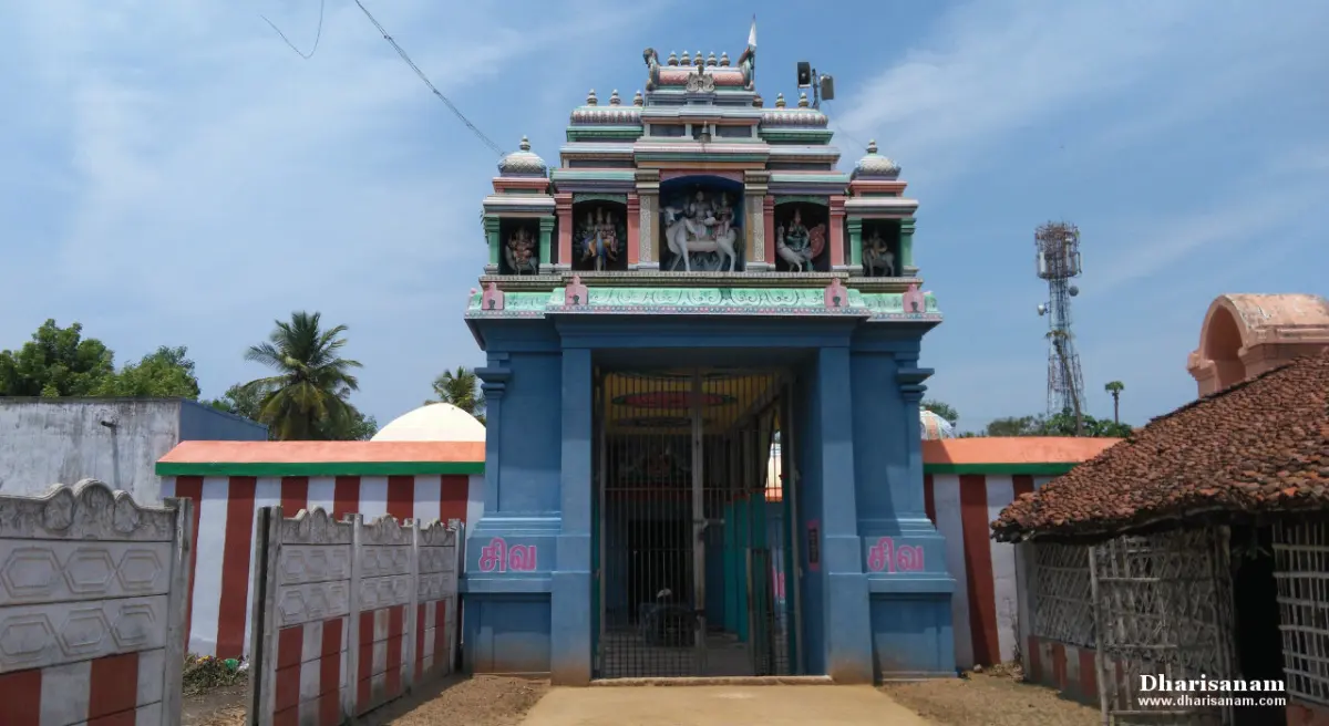 A blue gateway with a painted upper storey of sculpted deities, a barred door and striped walls.