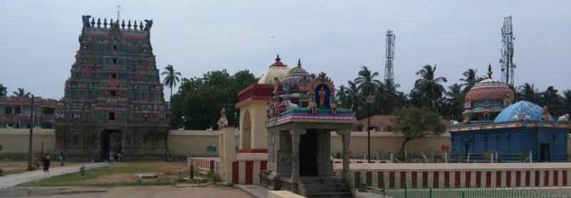 A tall carved tower on the left, a shrine with painted figures and a blue domed shrine on the right