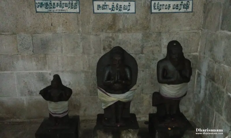 Three black stone idols against a wall, with Tamil name boards above them