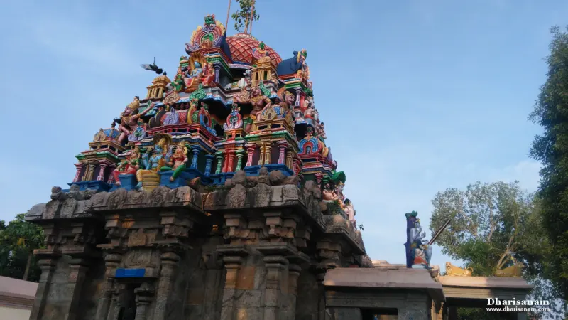 A tower covered with painted figures and a red dome, rising over a stone base, with a bird in flight at the left