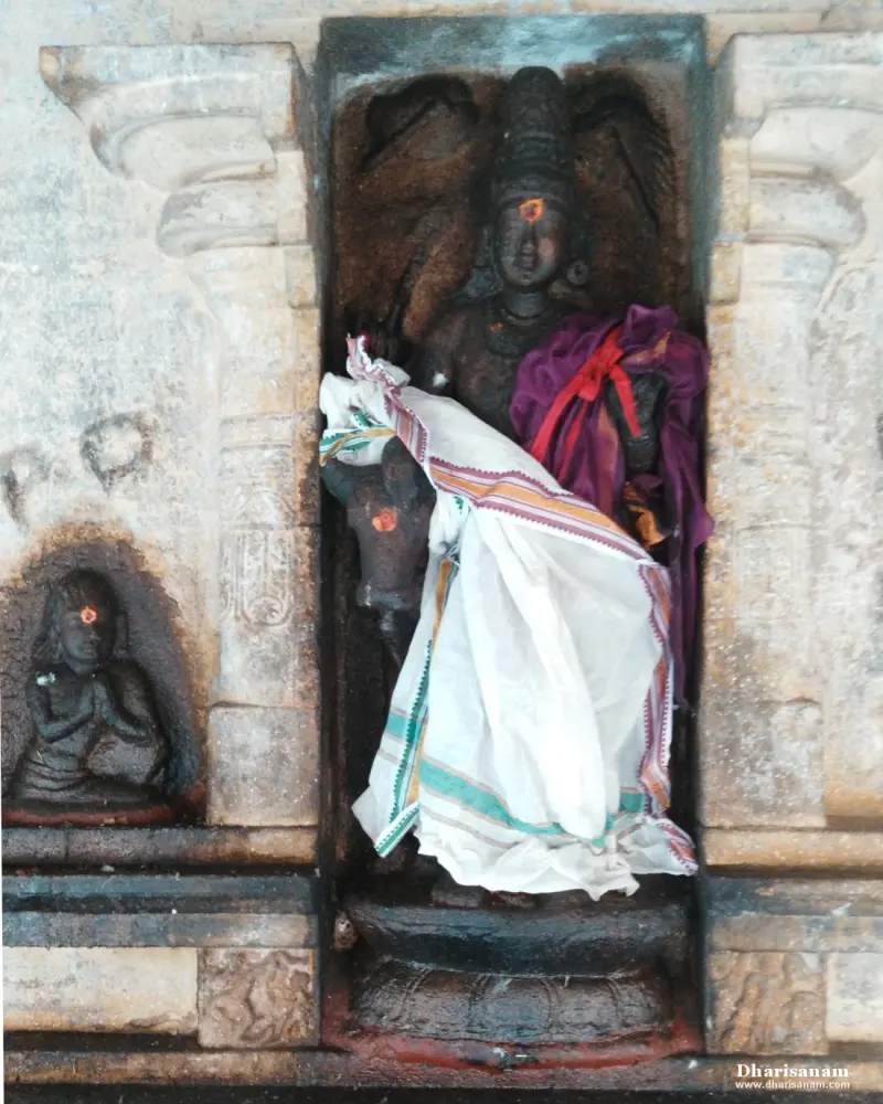 Stone figure in a niche with a bull's head beside it, draped in white and purple cloth