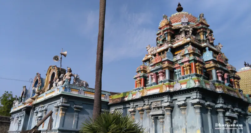 A colourful tiered tower with a red domed top beside a blue-grey roof with bulls and figures, under a bright sky