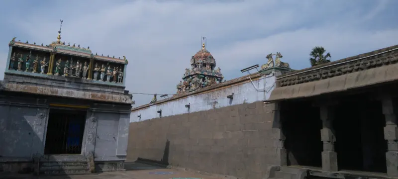 Row of saint statues along a shrine roof, tower behind the wall