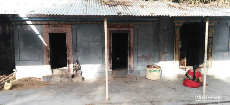 Three shrine doorways with name boards under a tin roof, a woman seated at the right
