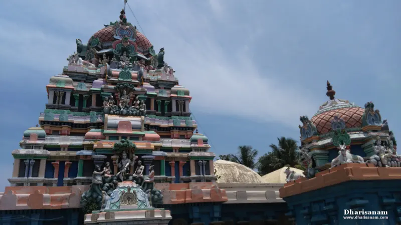 A tall painted tower of many tiers with sculpted figures, and a smaller domed shrine on the right.