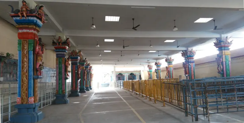 A long covered hall with queue railings and painted pillars