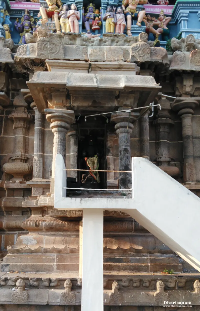Small stone shrine set on a tower wall with a white stair leading up to it and painted figures above