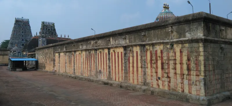 Long red-striped wall with gopurams rising beyond