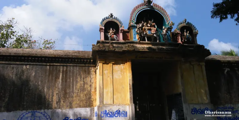 Sculpted deities atop the yellow entrance arch against a blue sky