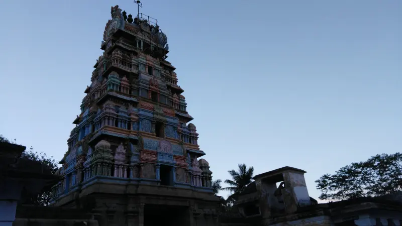 Tall tiered gopuram with painted figures against a clear evening sky