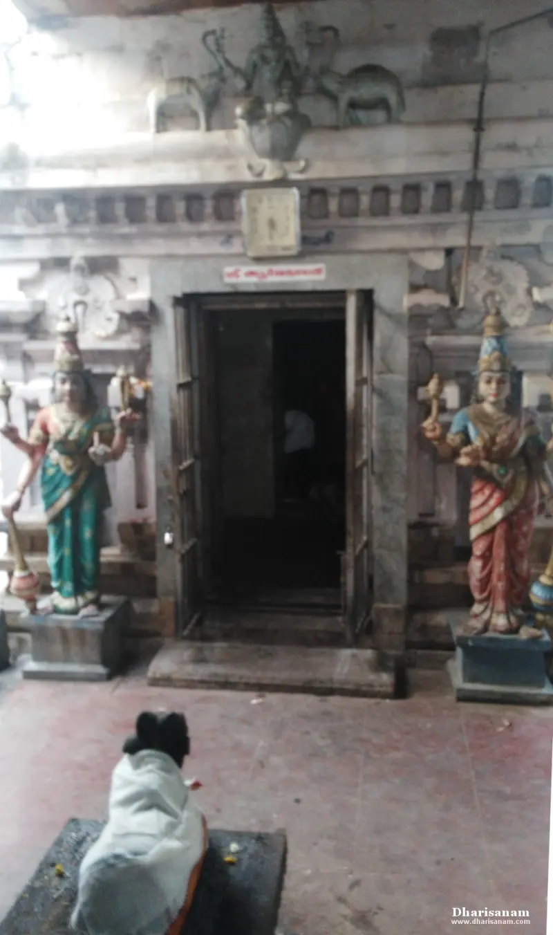 Dark doorway framed by two painted standing figures, with a Nandi in white cloth before it