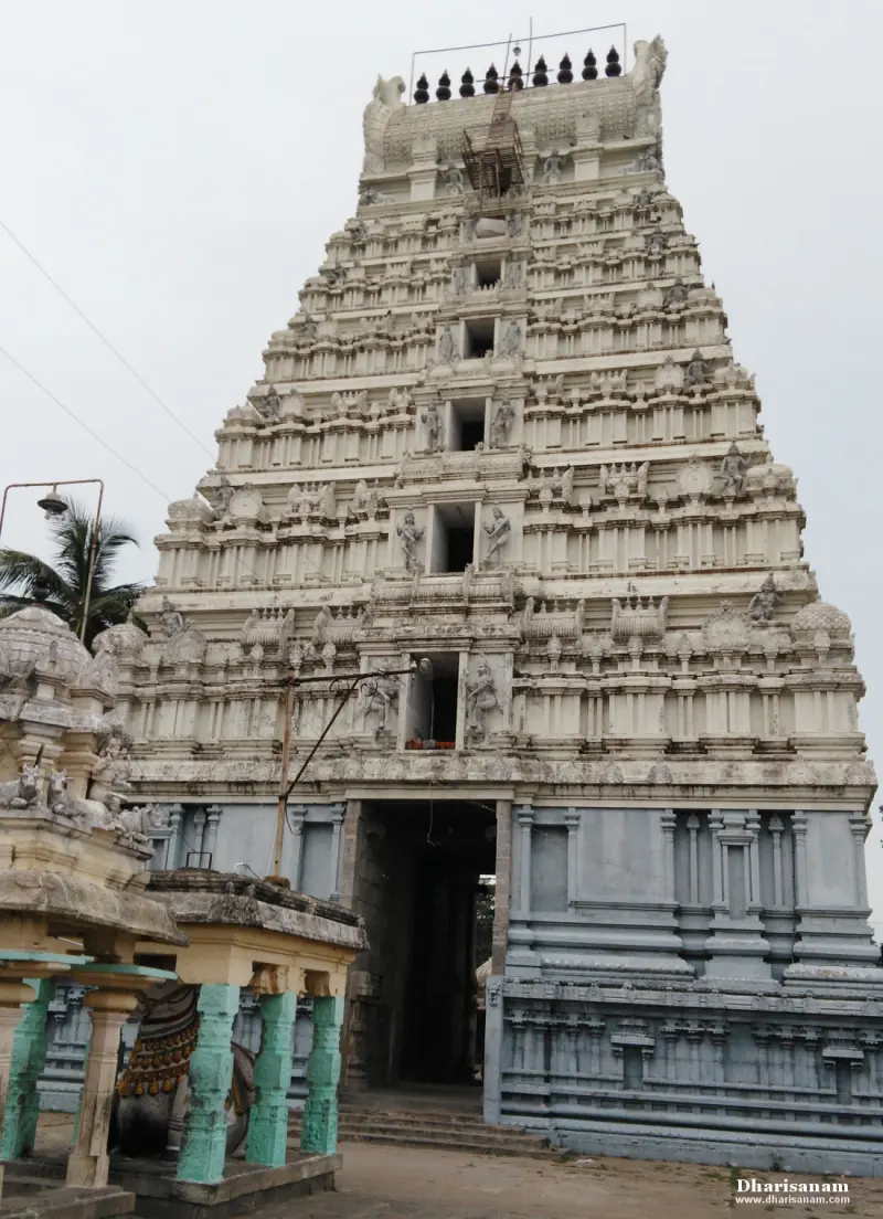 A tall tiered tower in pale stone above the entrance, with a Nandi under a green-pillared canopy at left