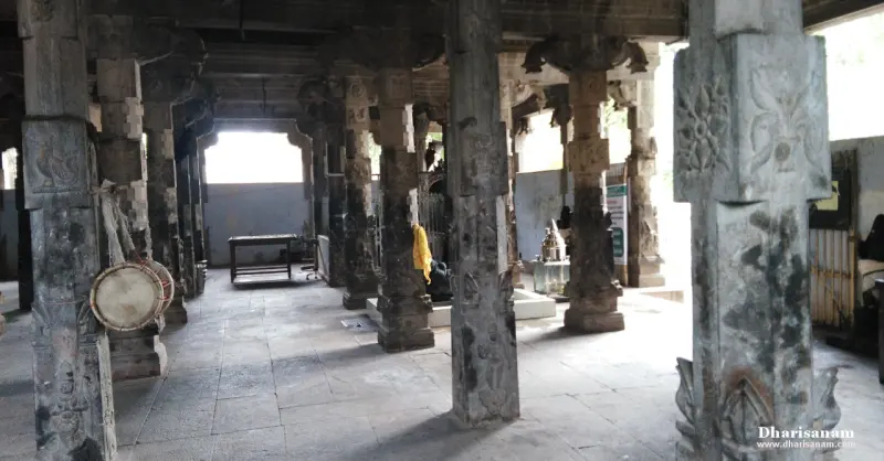 Stone pillared hall with a large drum on the left and a lamp stand in the distance