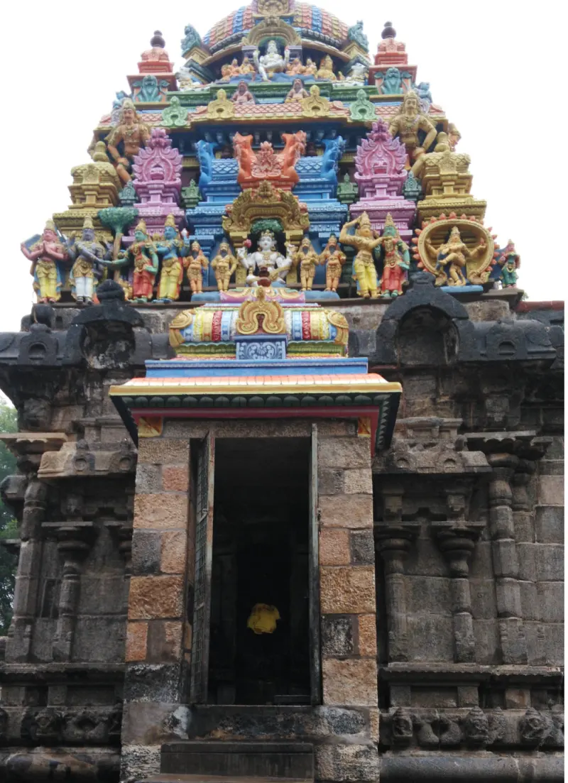 A stone doorway with a brightly painted tower of small figures above it.