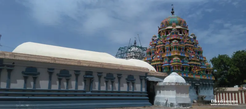 A painted temple tower rising behind a long white barrel-roofed hall, with a small white shrine in front