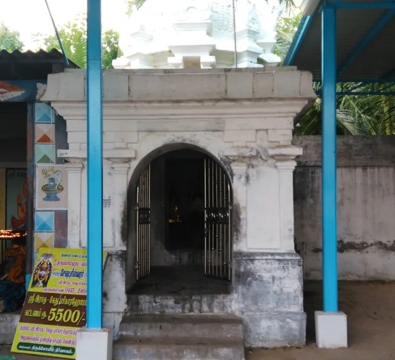 A white shrine with an arched iron gate, with a sign for Raghu-Kethu pariharam at lower left.