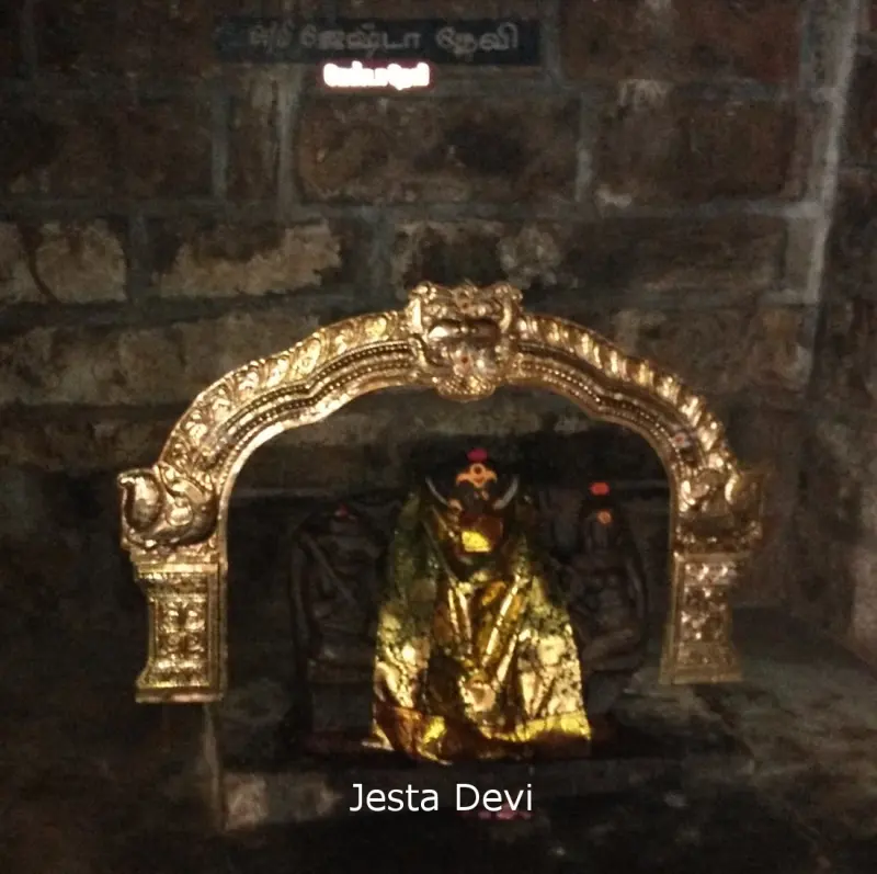 A figure wrapped in golden cloth inside a gilded arch on a stone wall, under a name board
