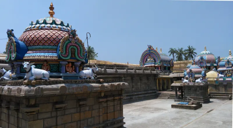 Painted shrine domes with white bull figures above a stone wall, around an open paved courtyard