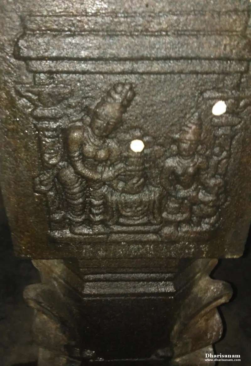 A carved relief of two standing figures on either side of a seated lingam form.