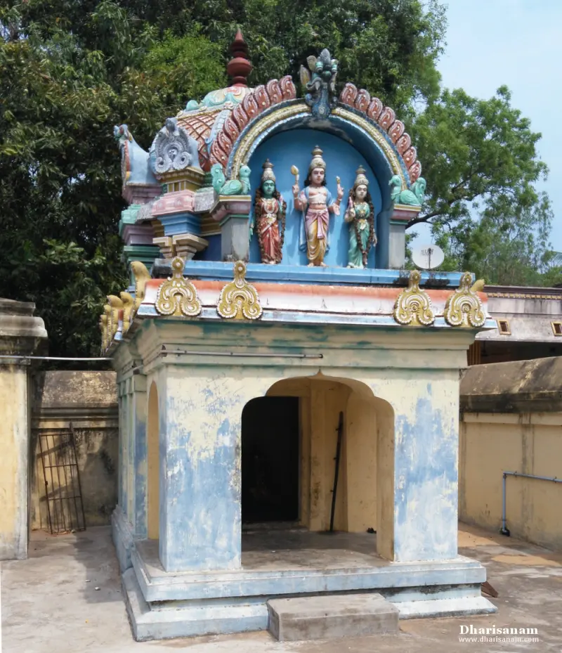 Small shrine with an arched doorway and three painted figures in a blue niche on its roof
