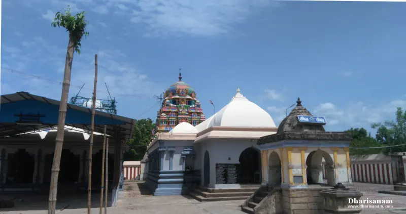 White domed temple roofs, a small stone shrine with arches at right, and a painted tower behind