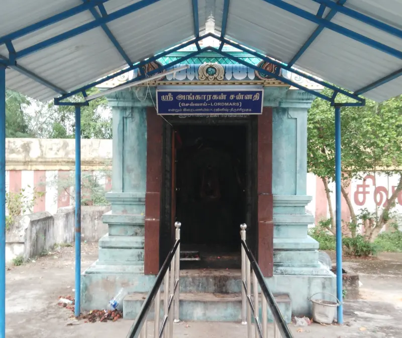A small shrine under a blue canopy, with a blue Tamil board naming it the shrine of Ankarakan.