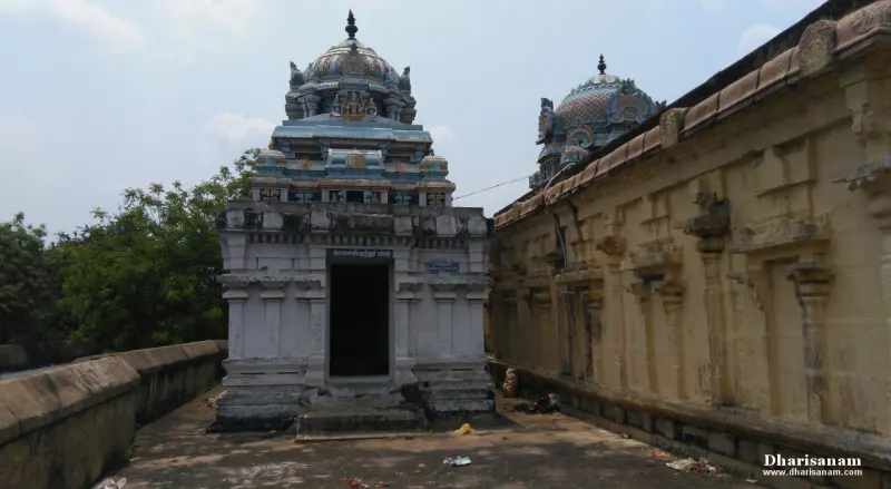 Small white shrine with a sculpted tower on a rooftop corridor