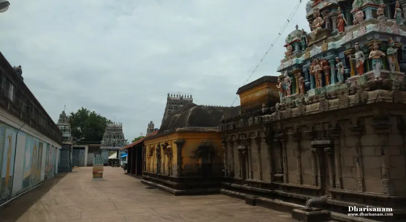 A wide stone-paved corridor with painted panels on the left and a stone wall with a painted tower on the right
