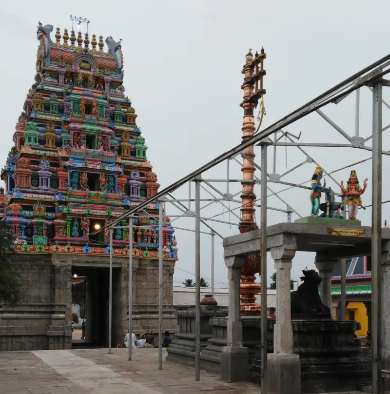 Colourful tower beside a tall copper flag post and a Nandi shrine