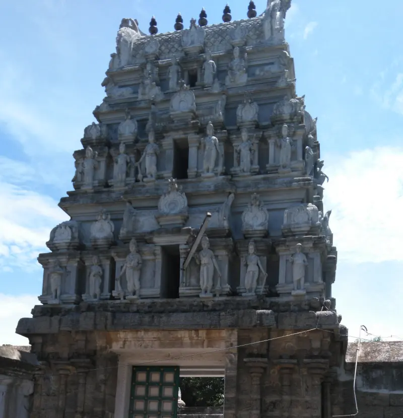 A tiered gateway tower covered with stone figures, above an old stone entrance with a green door.