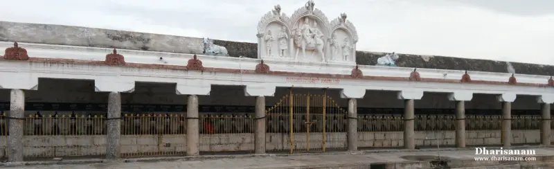 A long pillared corridor with idols in a row behind railings and a white carved gable above the middle