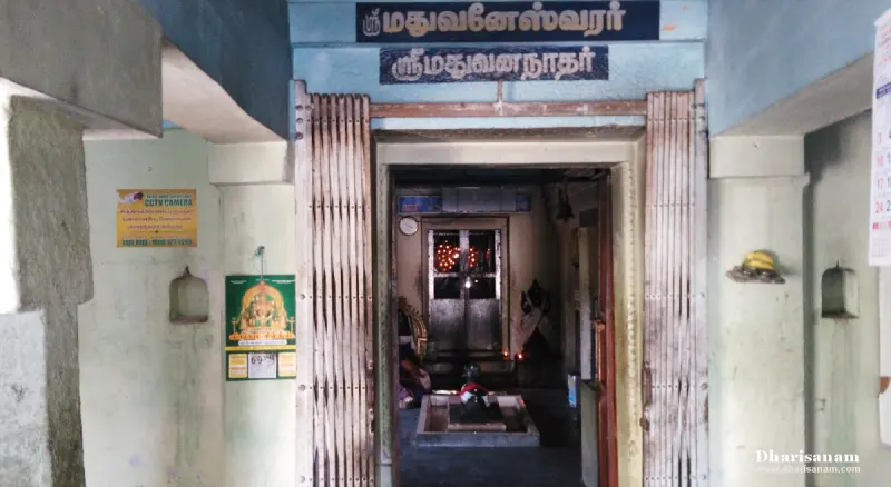Entrance of a shrine with a lingam inside, a Tamil name board above and an iron folding gate