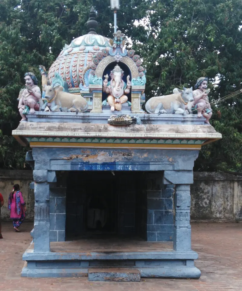 A small open shrine with a Ganesha figure and two bulls on its roof