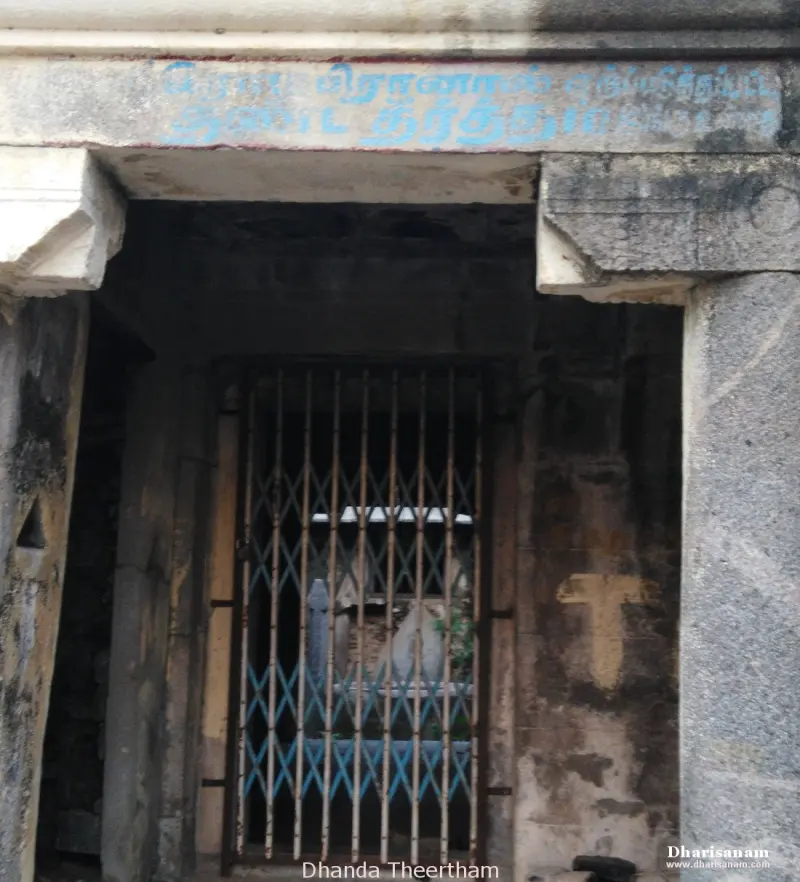 A narrow stone doorway closed with an iron gate, a name painted above and printed below
