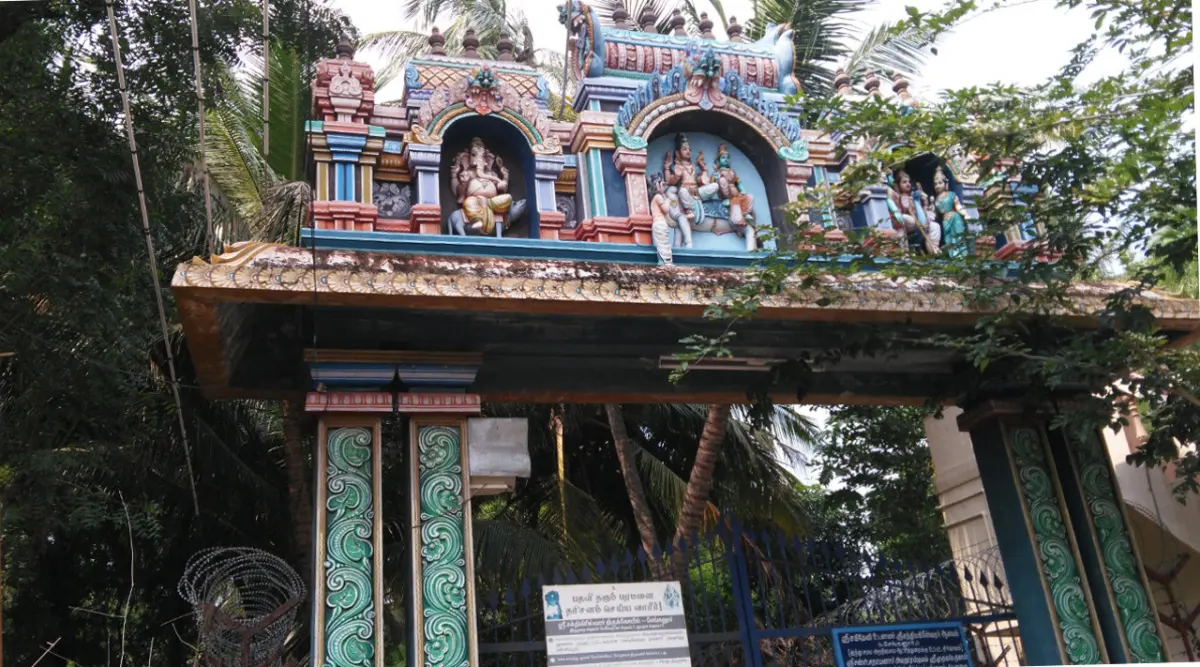 Painted archway with deity sculptures above a gated temple entrance