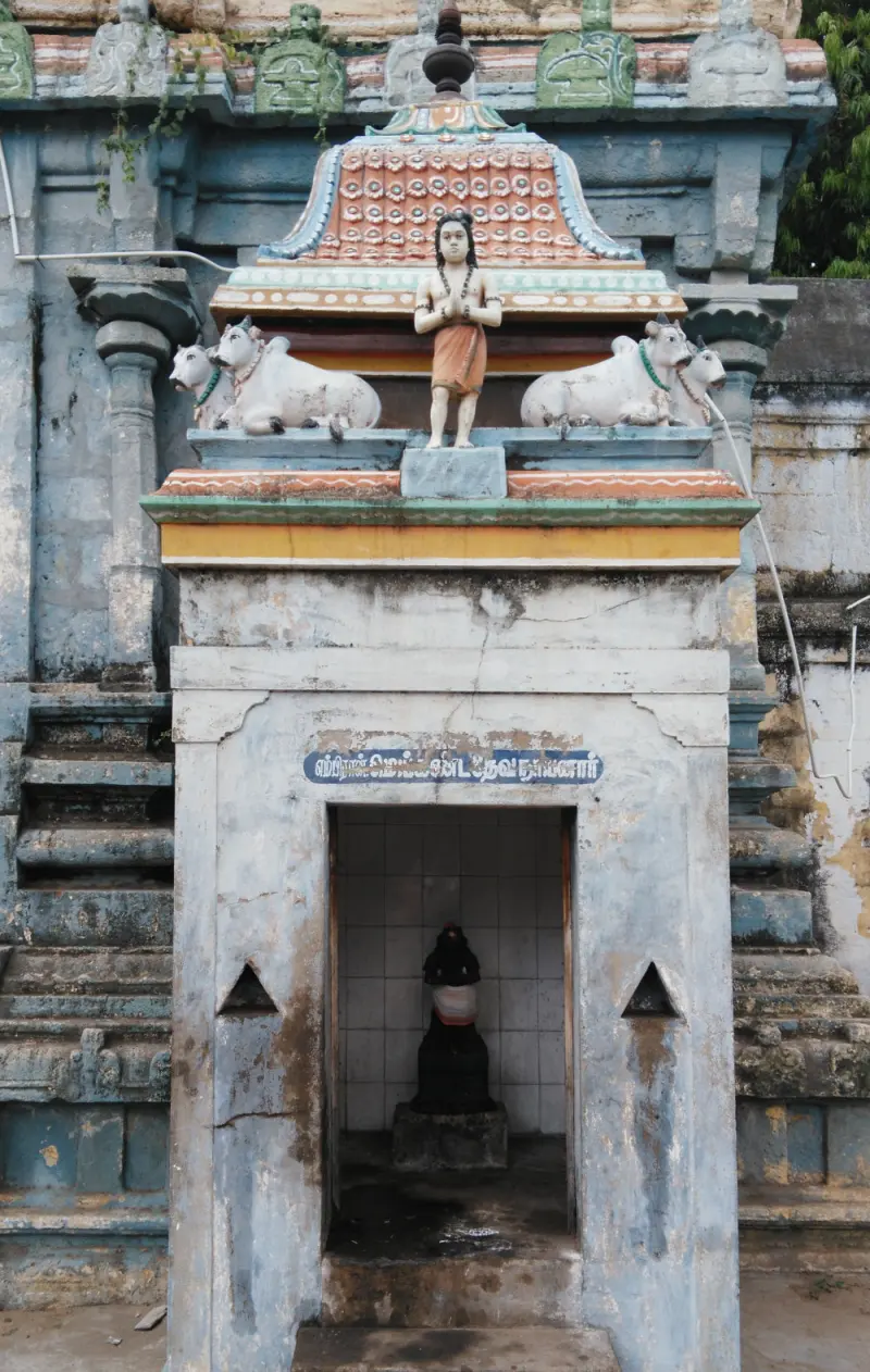 Small shrine with a painted gable, bulls on either side, and a black idol inside