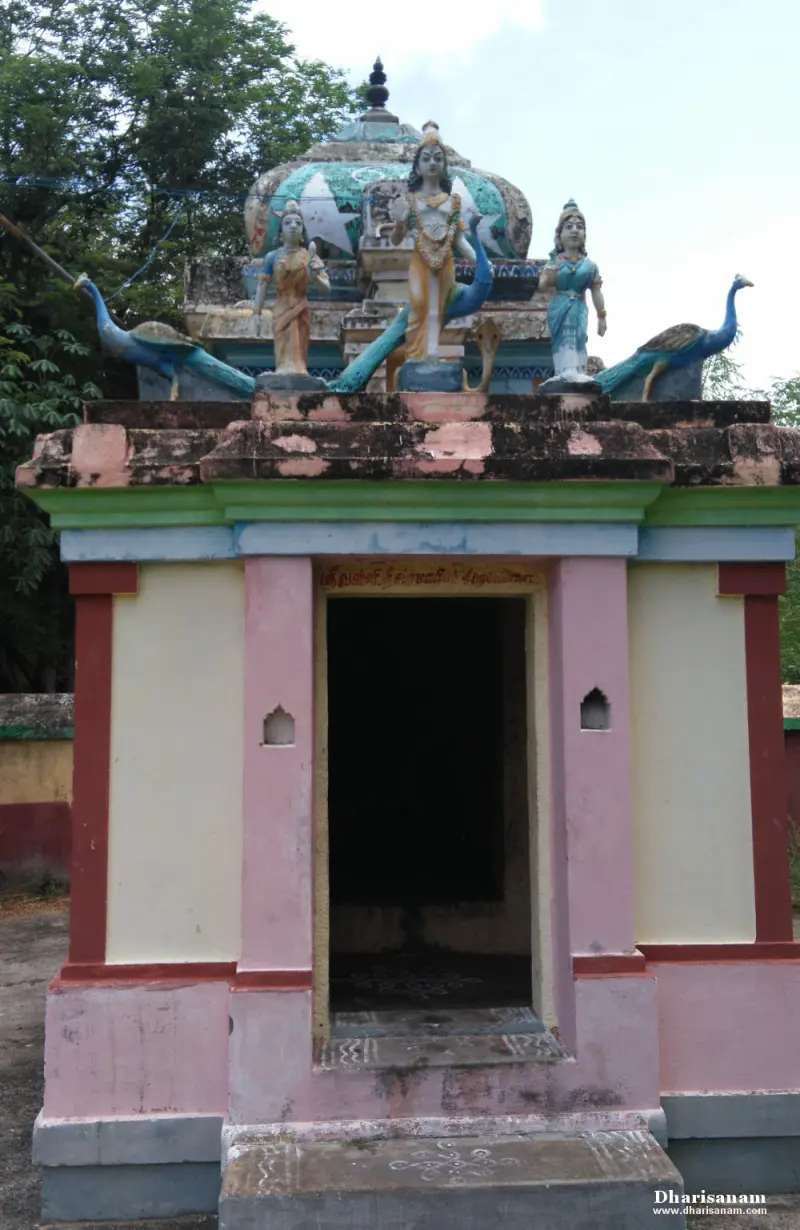 A pink and cream shrine with an open doorway; two peacocks and three standing figures on the roof