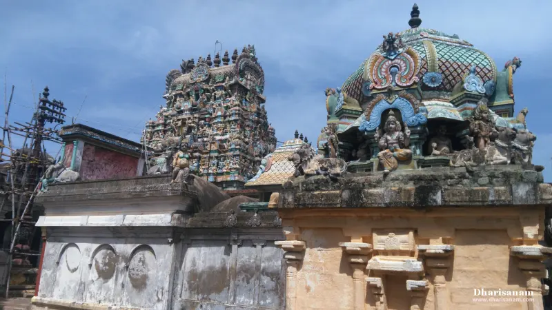 A domed shrine roof with figures beside a wall, and a tall tower behind