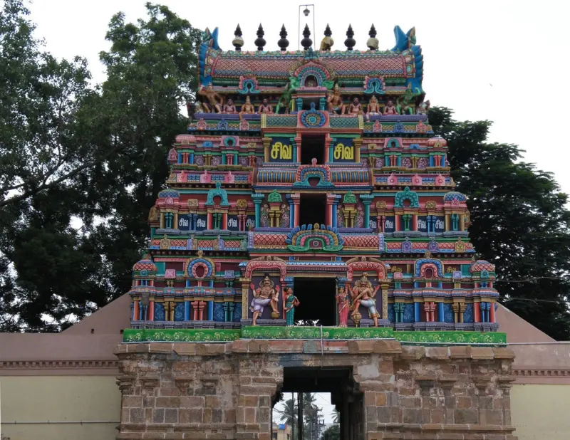 Tall colourful temple tower with rows of statues and Siva signs