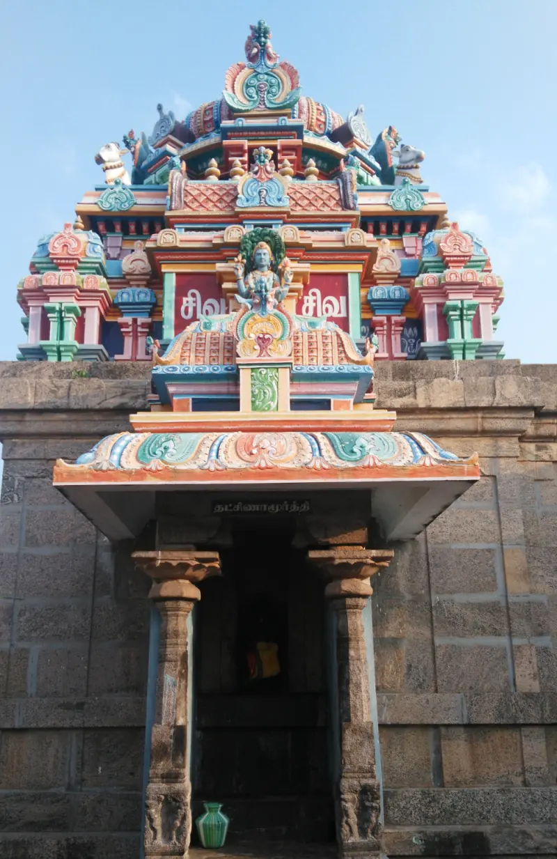A stone shrine with painted tower and Dakshinamurthy name board