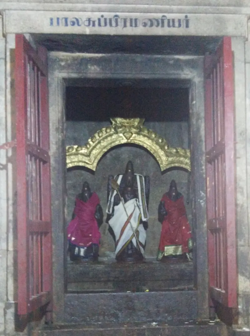 Murugan with vel between two goddesses under a gold arch