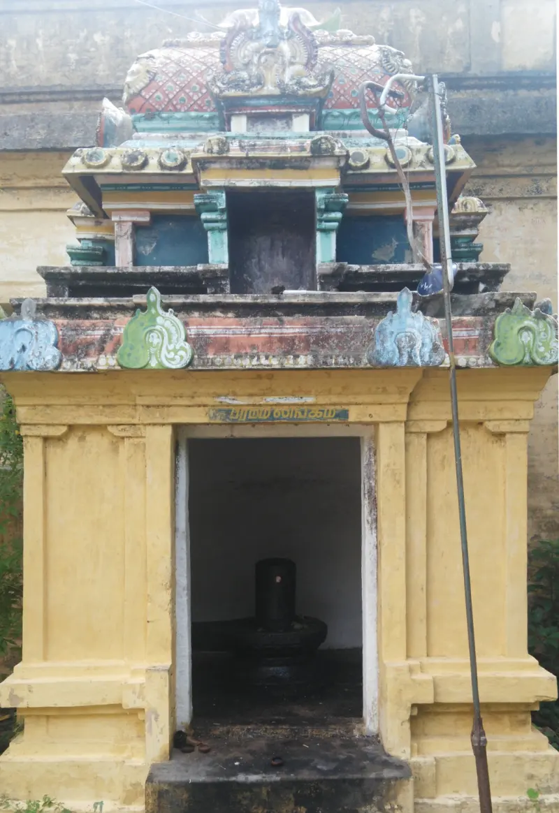 A yellow-walled shrine with a lingam visible inside the doorway