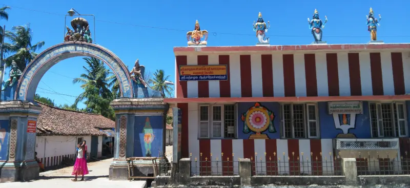 A gateway arch beside a red and white striped temple wall