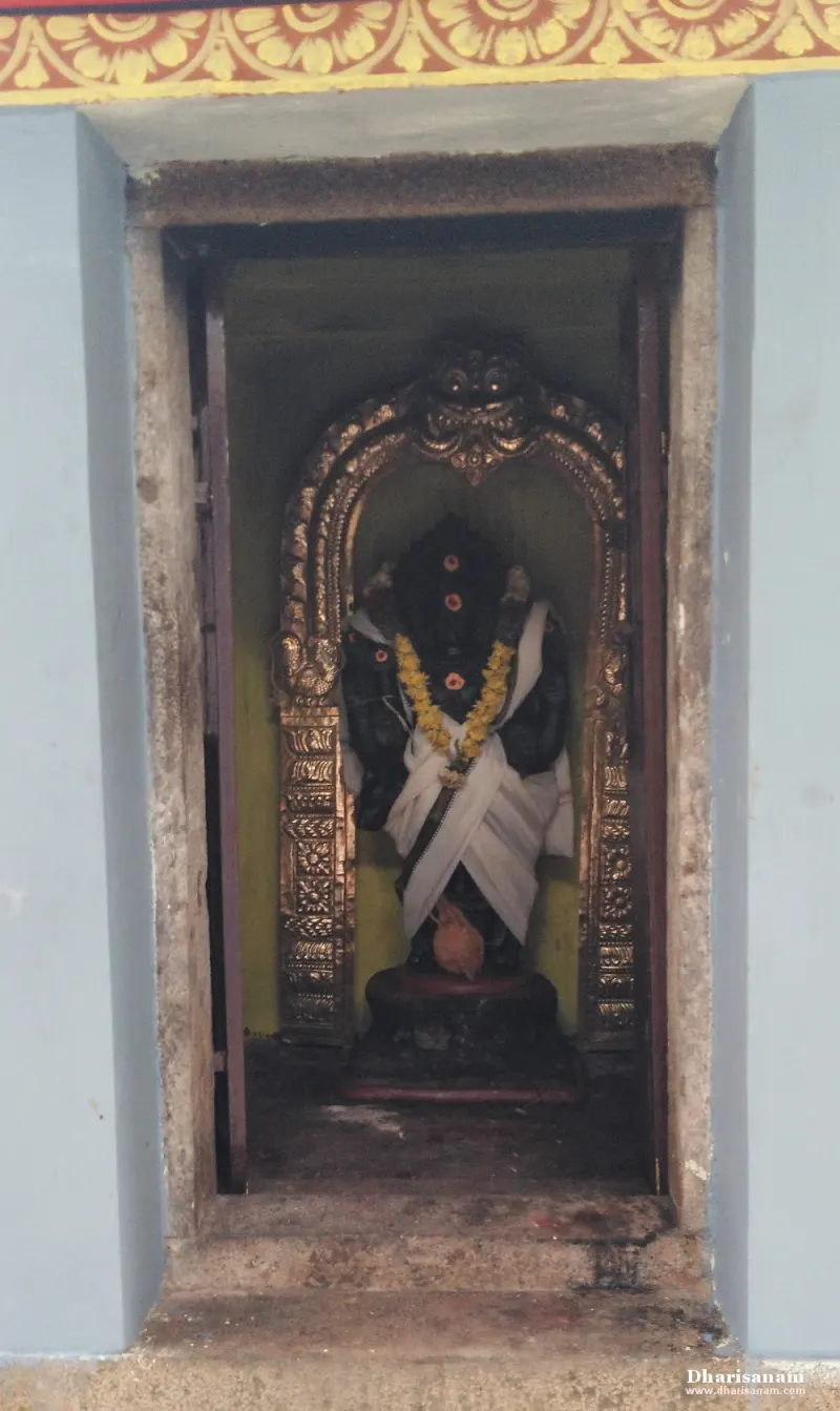 A dark image in white cloth and a yellow garland, framed by a gilded arch in a blue wall