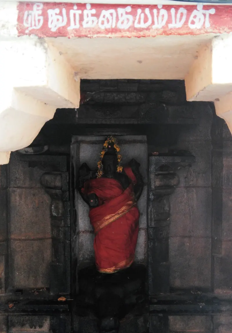 A dark Durgai idol in a red sari under a Tamil name board