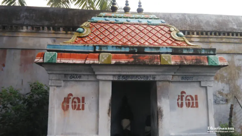 Small whitewashed shrine with a patterned red and orange roof and a dark doorway