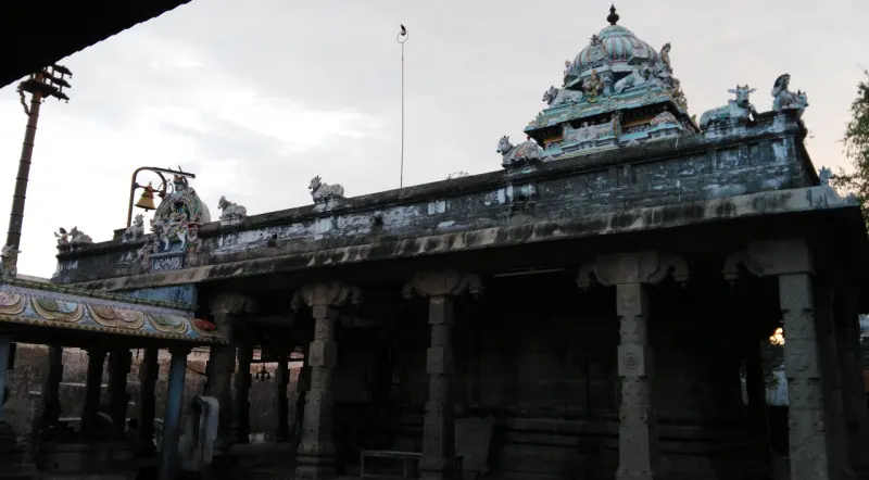 Long pillared hall with a small tower on top and a bell hanging at left