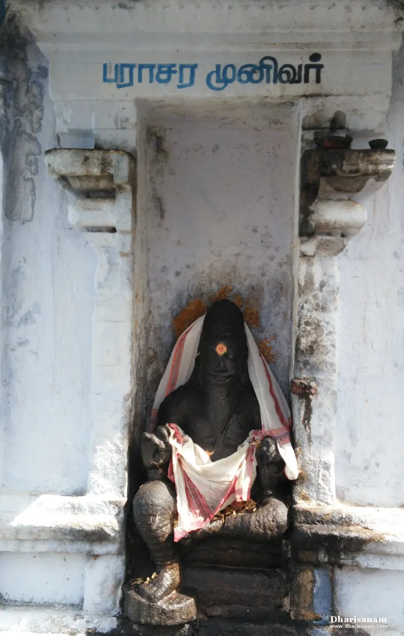 Dark idol in white cloth seated in a white wall niche, with the Tamil words for Parasara Munivar above